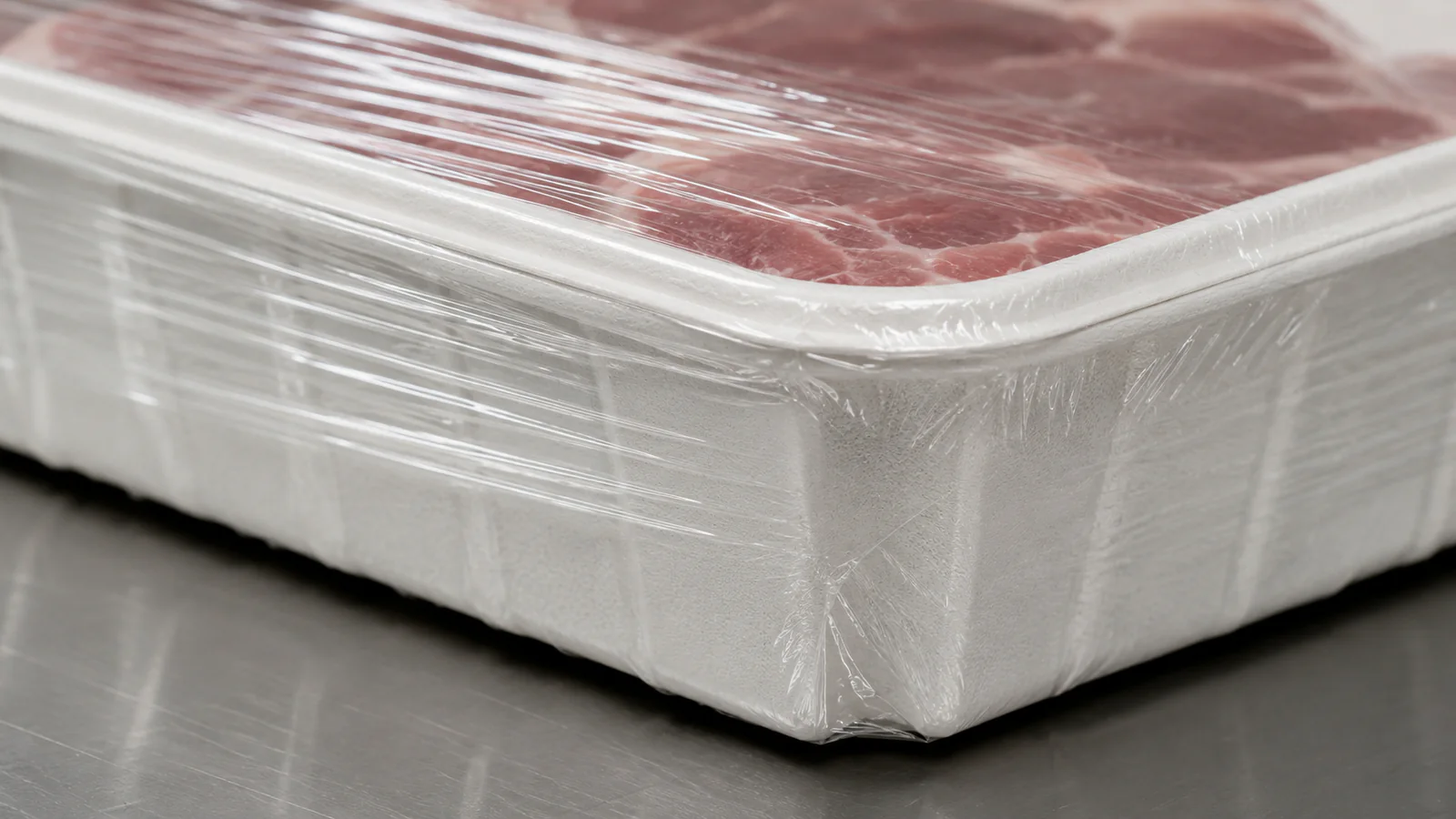 Bagasse food tray under overwrap film on a packing line